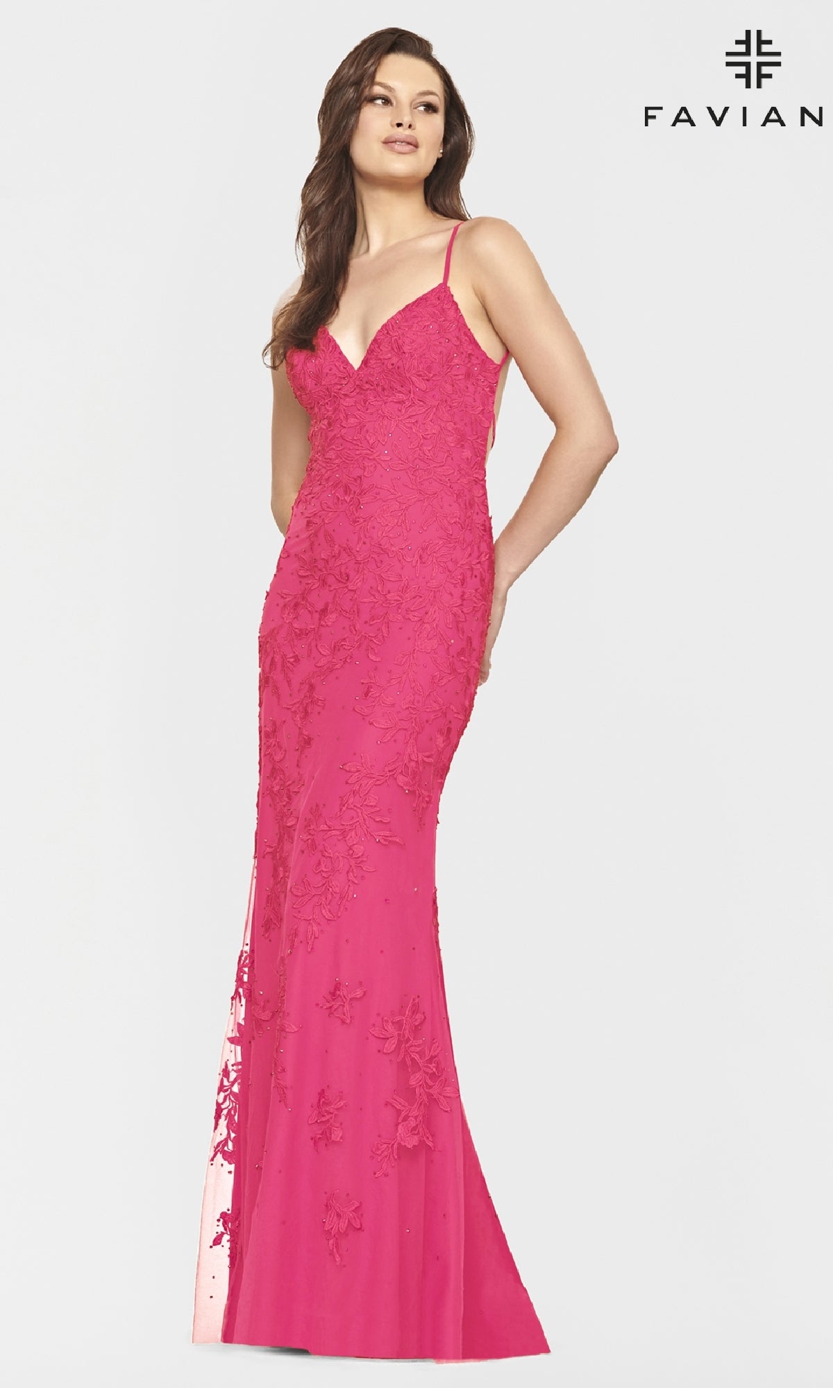 Woman wearing the Faviana Lace Embroidery Long Backless Prom Dress, a fitted, floor-length pink gown with floral lace details and thin straps, stands against a plain white background with the Faviana logo in the corner.